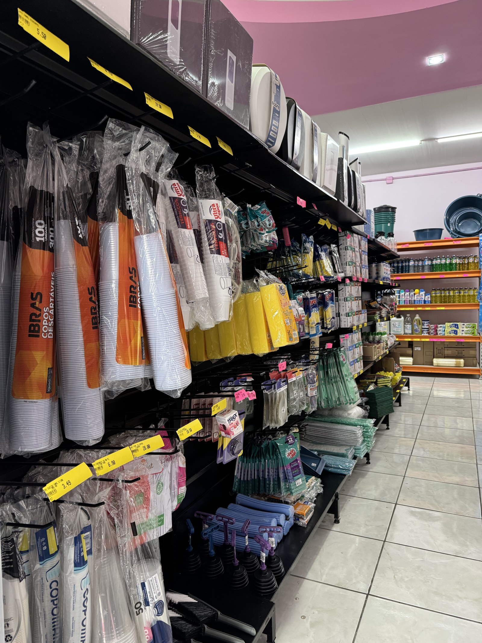 Prateleira com variedade de produtos de limpeza coloridos na loja Kaká Limpeza